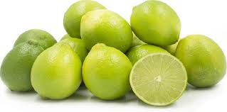 A bunch of fresh green limes, with one lime cut in half showing the juicy interior.