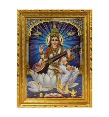 A framed picture of Goddess Saraswati seated on a white lotus, holding a veena, with a golden border frame.